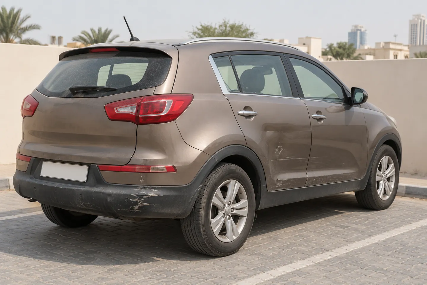 Used early-2010s bronze Sportage-style Kia SUV with rear bumper scuffs, lower-panel scratches and a shallow rear door dent